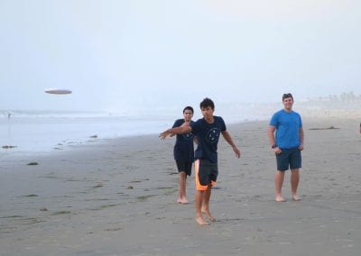 San Diego Christian College student play frisbee on the beach