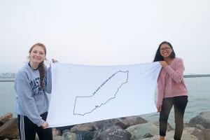 San Diego Christian College students pose beside the seashore with a map of California